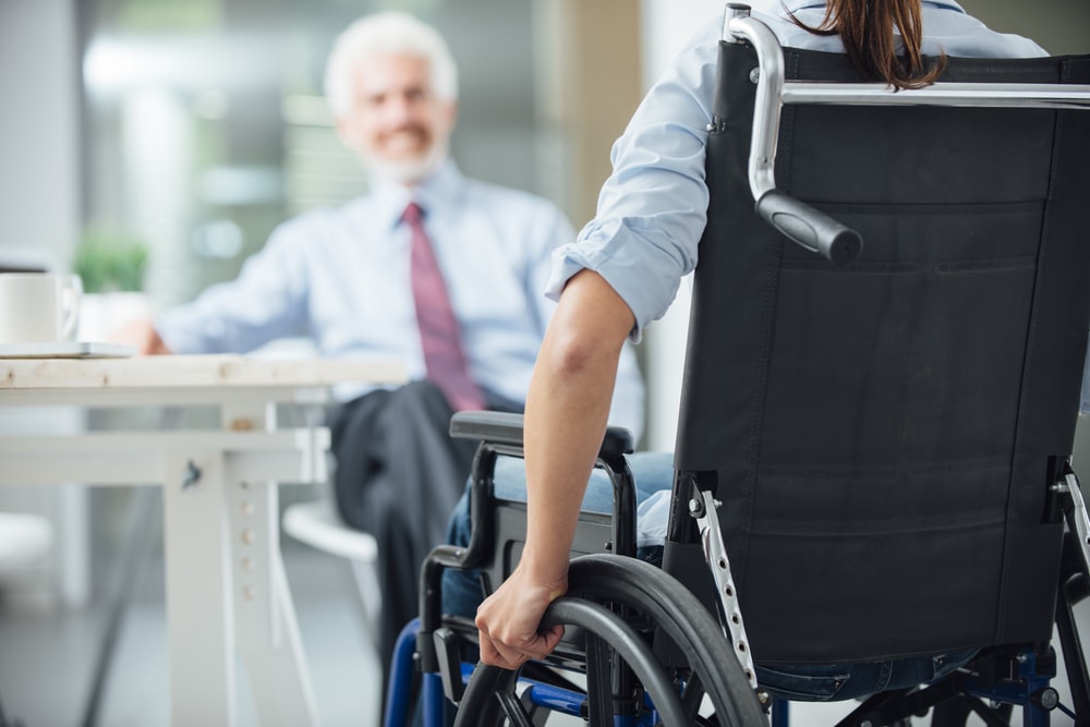 Homme en fauteuil roulant discutant dans un bureau 